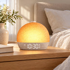 Soft Rise Sunrise Alarm Clock glowing on a wooden nightstand beside a bed